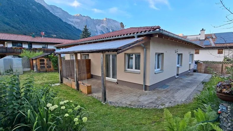 Einfamilienhaus mit großem, gepflegtem Garten, überdachter Terrasse und beeindruckendem Bergblick.