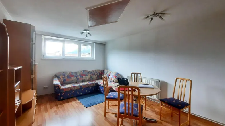 Helles Wohn- und Esszimmer mit Holzboden, gemütlichem Sofa und Esstisch unter Dachschräge.