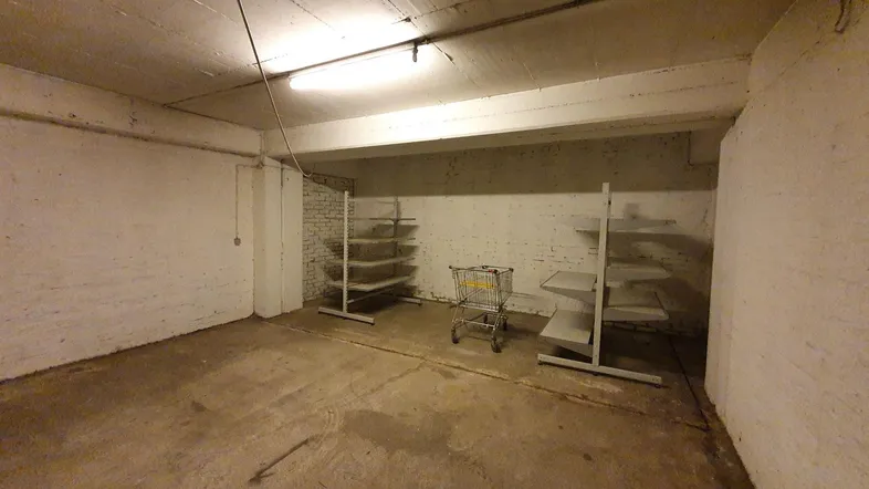 Geräumiger Kellerraum mit Betonboden, weiß gestrichenen Ziegelwänden und einfacher Beleuchtung.