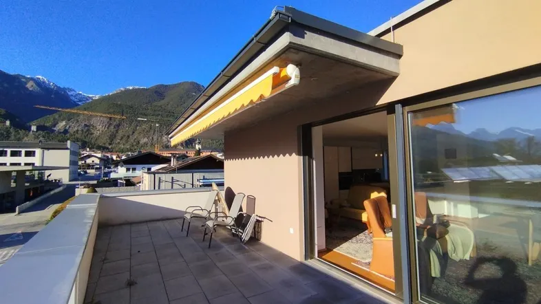 Sonnige Terrasse mit Bergblick und Zugang zum Innenbereich, ausgestattet mit einer Markise.