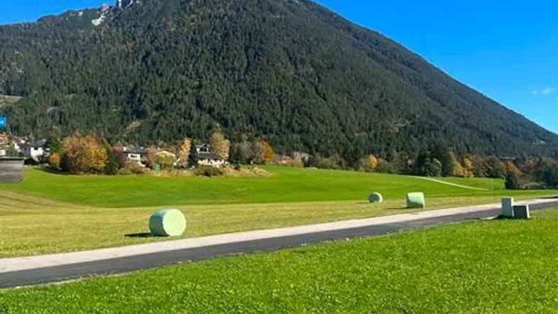 Malerische Landschaft mit grünen Feldern, einem großen Berg und klarem blauen Himmel.