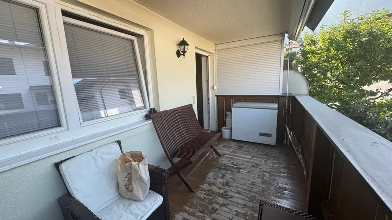 Geräumiger Balkon mit Sitzgelegenheiten, einem Gefrierschrank und Blick auf die Umgebung.