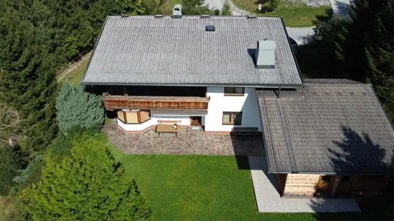Luftaufnahme eines traditionellen Hauses mit Satteldach, Garten und umliegenden Bäumen.