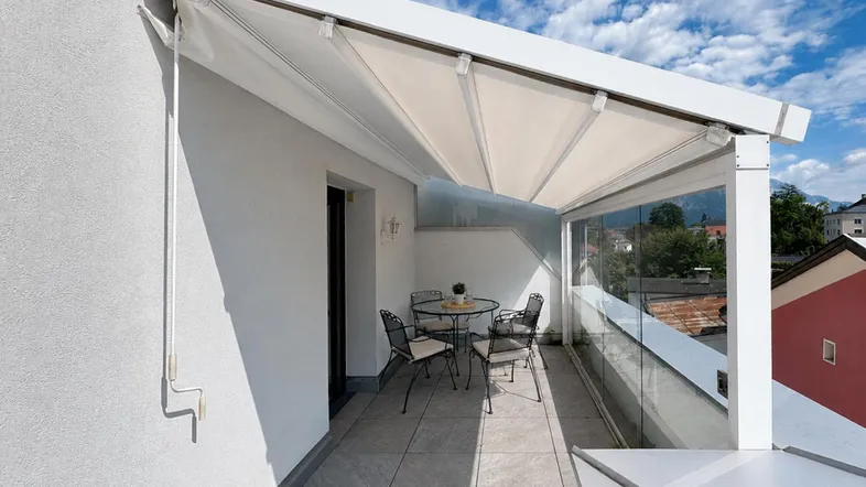Geräumige Terrasse mit Markise, Sitzgelegenheiten und Panoramablick auf die Berge und die Umgebung.