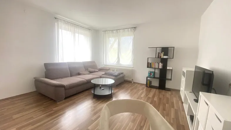 Helles Wohnzimmer mit beigem Sofa, Holzboden und modernen Möbeln, ideal zum Entspannen.