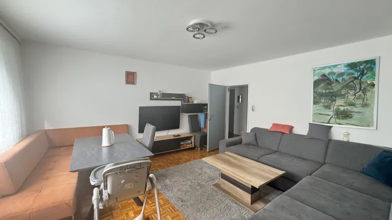 Geräumiger Wohn-Essbereich mit bequemer Eckcouch, Esstisch und Parkettboden, ideal für Familienleben.