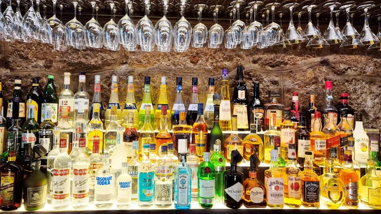 Eine gut bestückte Bar mit vielen Flaschen und hängenden Gläsern, beleuchtet von unten.