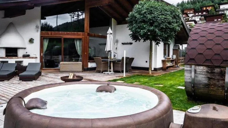 Außenbereich mit aufblasbarem Whirlpool, Holzterrasse und gepflegtem Rasen vor dem Haus.