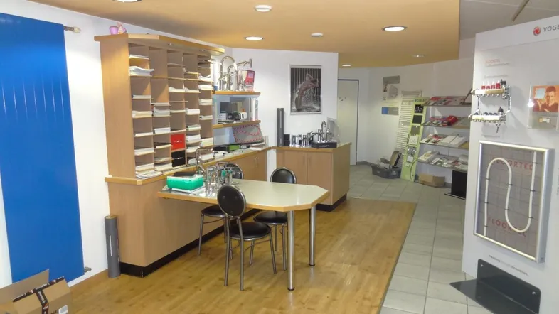 Geräumiger Gewerberaum mit Holzboden, Einbauregalen und verschiedenen Ausstellungsstücken, ideal für Büro oder Showroom.