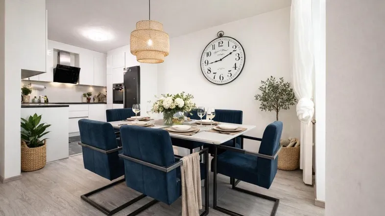 Helles Esszimmer mit modernem Esstisch, blauen Stühlen und offener Küche im Hintergrund.