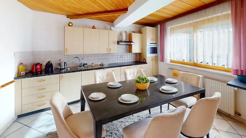 Geräumige Küche mit Essbereich, Holzdecke und hellen Einbauschränken sowie Fliesenboden.