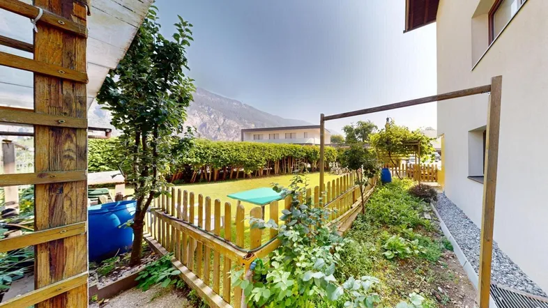 Gepflegter Gartenbereich mit Holzzaun, Grünflächen und einem kleinen Schuppen.