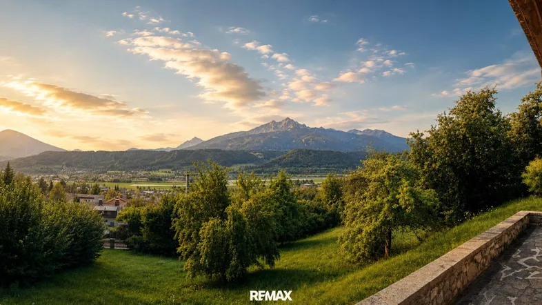 Panoramablick auf die Berge bei Sonnenuntergang von einer Terrasse mit viel Grün und warmem Licht.