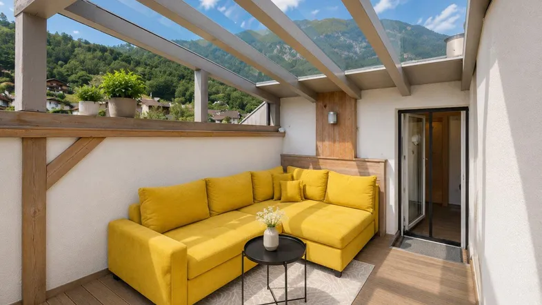Gemütliche Terrasse mit gelbem Sofa, Glasdach und atemberaubendem Bergblick, ideal zum Entspannen.