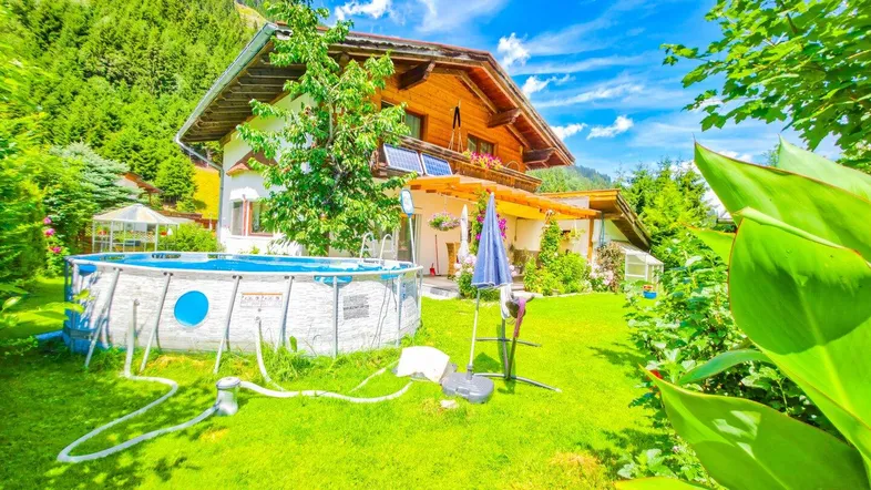 Großzügiger Gartenbereich mit Aufstellpool, umgeben von grüner Natur und Bergen.