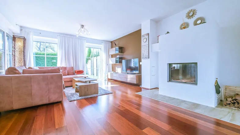 Helles Wohnzimmer mit Holzboden, Kamin und Zugang zur Terrasse, modern eingerichtet.