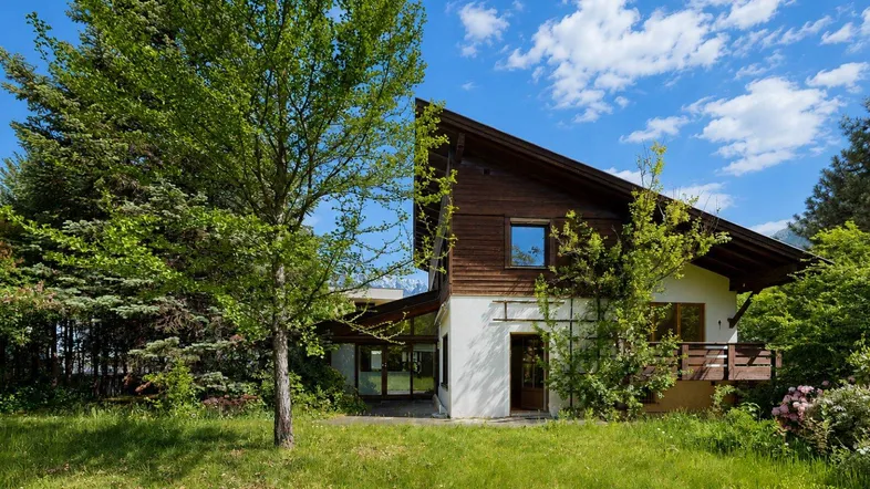 Traditionelles Haus mit Holzfassade und großem Garten in grüner Umgebung.