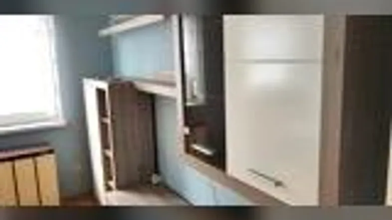 Zimmer mit eingebauten Möbeln und einem Fenster, das Tageslicht hereinlässt.