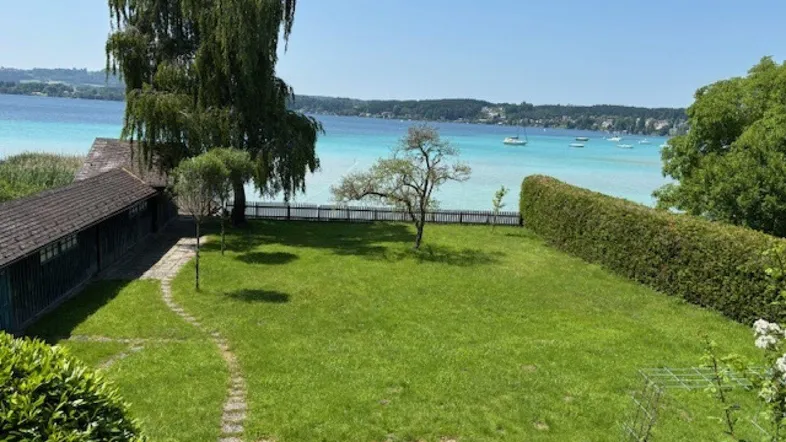 Großer grüner Garten mit Rasenfläche, Baumbestand und direktem Blick auf den See.