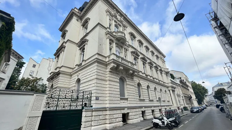 Elegantes Altbaugebäude mit reich verzierter Fassade und Balkonen an einer städtischen Straße.