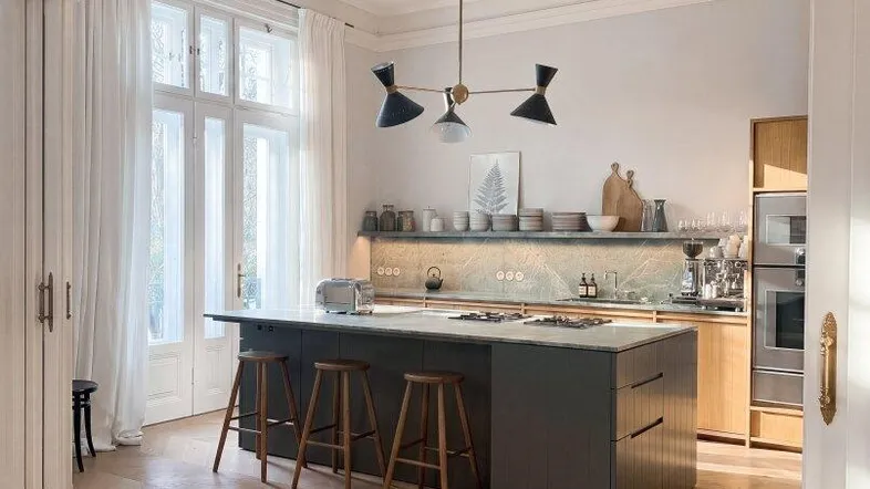 Moderne offene Küche mit Kücheninsel, Holzboden und großen Fenstern, die viel Tageslicht hereinlassen.