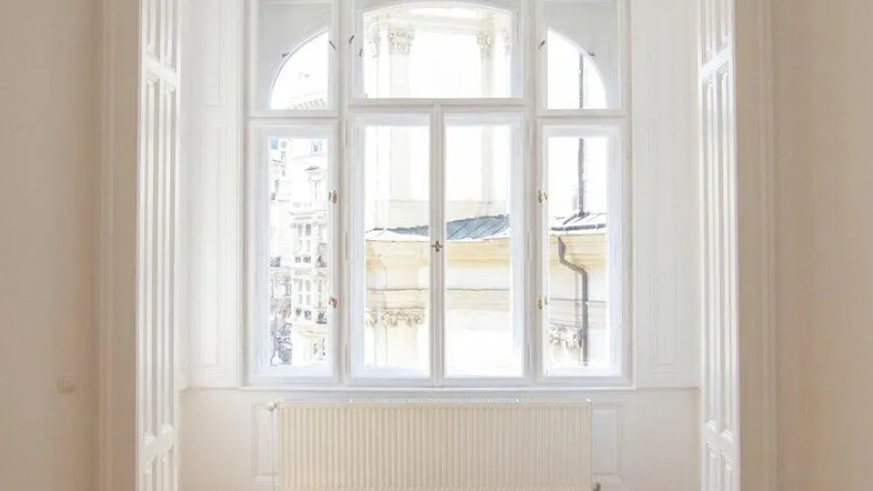 Heller Raum mit elegantem Fischgrätparkett, hohen Decken und großen, bogenförmigen Fenstern, die viel Tageslicht hereinlassen.