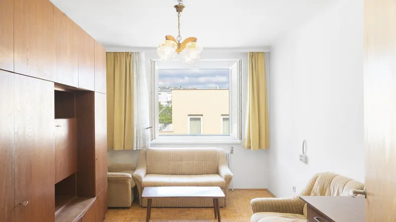 Helles Wohnzimmer mit Holzmöbeln, Parkettboden und Blick aus dem Fenster.