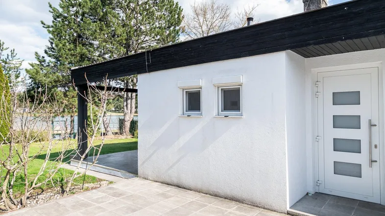 Eingangsbereich des Hauses mit gepflasterter Terrasse und Blick auf die grüne Umgebung.