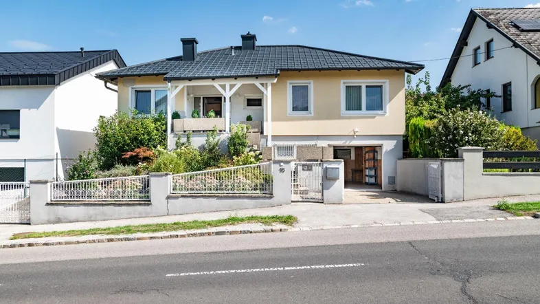 Traditionelles Einfamilienhaus mit gepflegtem Vorgarten und sonniger Veranda.