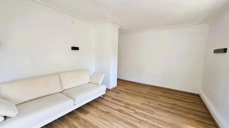 Helles Wohnzimmer mit modernem Sofa und Laminatboden, ideal für entspannte Stunden.