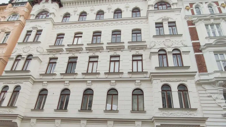 Historische Fassade eines Altbaus mit vielen Fenstern und dekorativen Elementen.