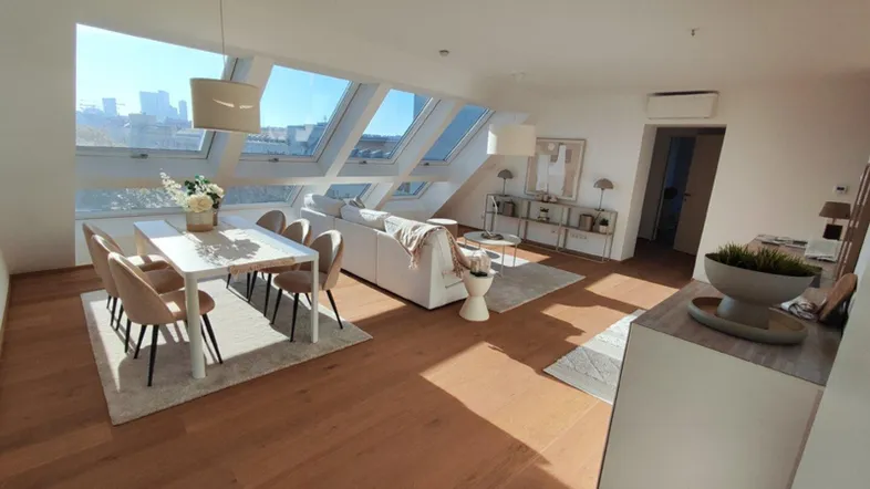 Heller, offener Wohn- und Essbereich mit Holzboden, modernen Möbeln und großen Dachfenstern mit Stadtblick.