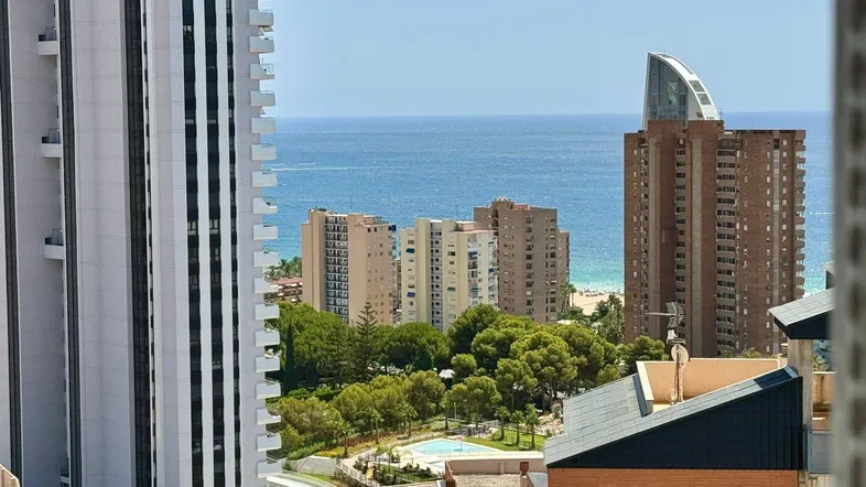 Panoramablick auf die Stadt mit Hochhäusern, Meer und einem Gemeinschaftspoolbereich.
