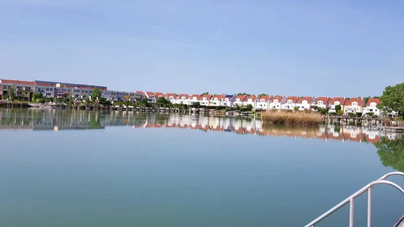 Seeblick auf eine Reihe von modernen Wohnhäusern am Ufer unter blauem Himmel.