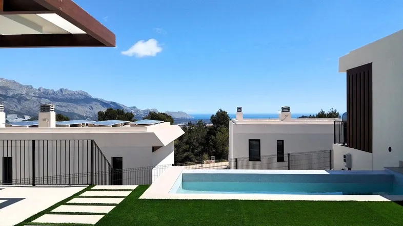 Moderner Außenbereich mit Pool, Kunstrasen und weitem Blick auf das Meer und die Berge.