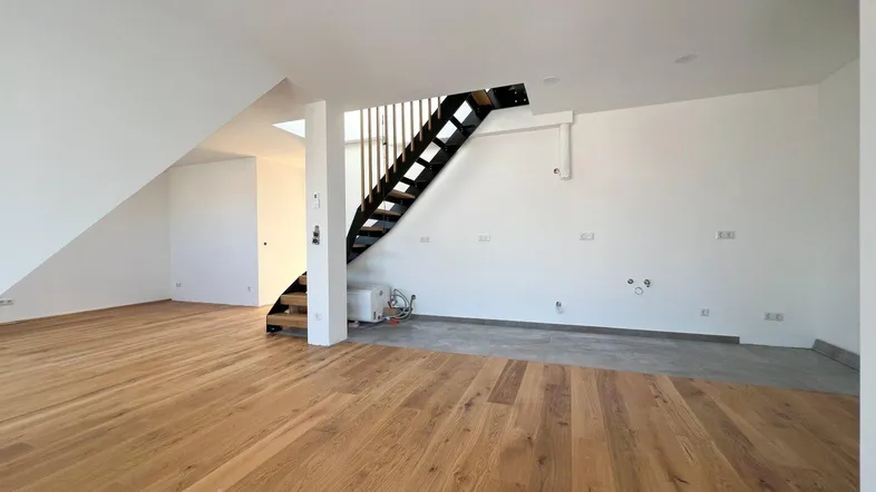 Geräumiger, heller Wohnbereich mit neuem Holzboden und moderner Treppe, bereit für den Innenausbau.