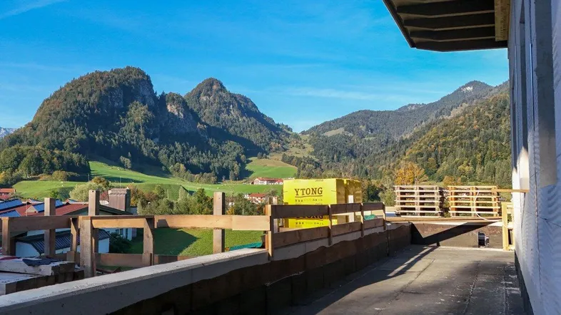 Blick von der Baustelle auf die umliegende Berglandschaft unter blauem Himmel.