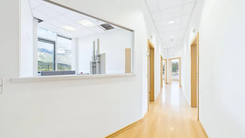 Heller Flur mit Holzfußboden und Durchblick in ein angrenzendes Büro mit Bergsicht.