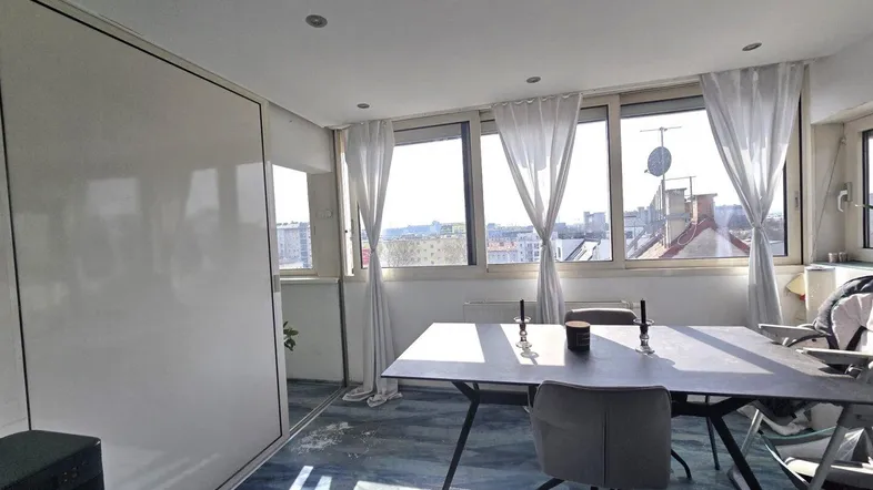 Heller Essbereich mit großem Tisch, vielen Fenstern und Stadtblick.