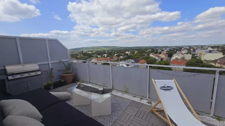 Große Dachterrasse mit Lounge-Möbeln, Grill und weitem Blick über die Stadt und Landschaft.
