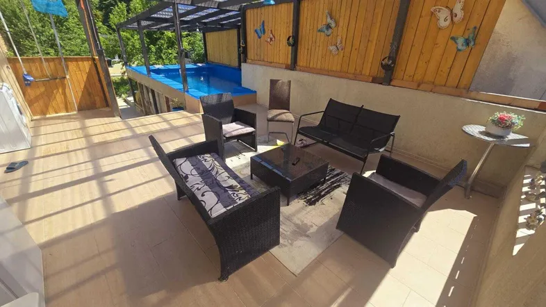 Überdachte Terrasse mit gemütlichen Sitzgelegenheiten und einem kleinen Pool im Hintergrund.
