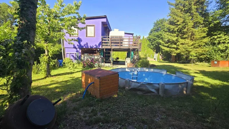 Großzügiger Gartenbereich mit einem oberirdischen Pool und einem farbenfrohen Haus im Hintergrund.