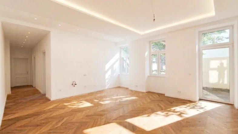 Helles, geräumiges Zimmer mit Fischgrätparkett und indirekter Deckenbeleuchtung, ideal für Wohnzwecke.