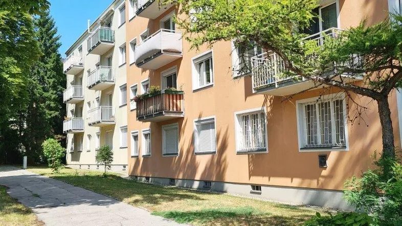 Mehrfamilienhaus mit mehreren Balkonen und Grünflächen in einer ruhigen Wohngegend.