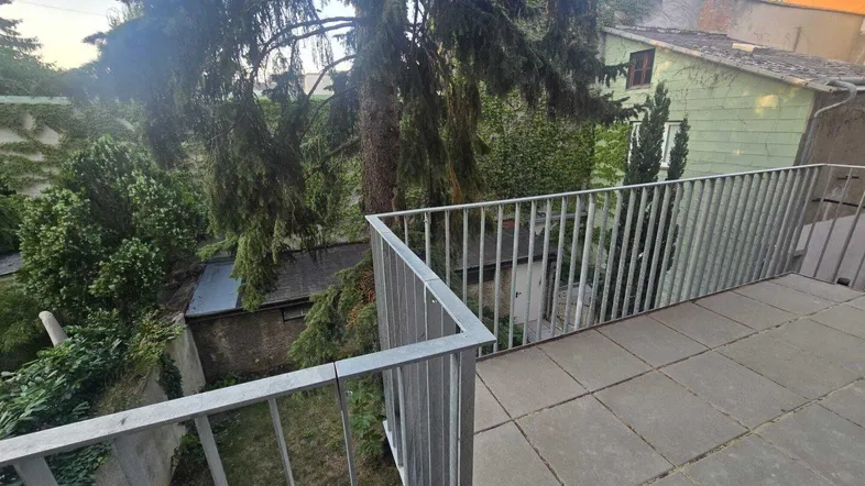 Geräumige Terrasse mit Metallgeländer und Blick ins Grüne, ideal für entspannte Stunden im Freien.