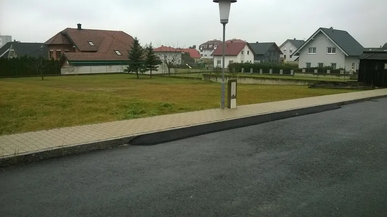 Unbebautes Grundstück mit Rasenfläche und angrenzender Straße in einer Wohngegend.