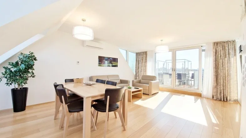 Heller Wohn- und Essbereich mit Holzboden, modernen Möbeln und direktem Zugang zur sonnigen Dachterrasse.