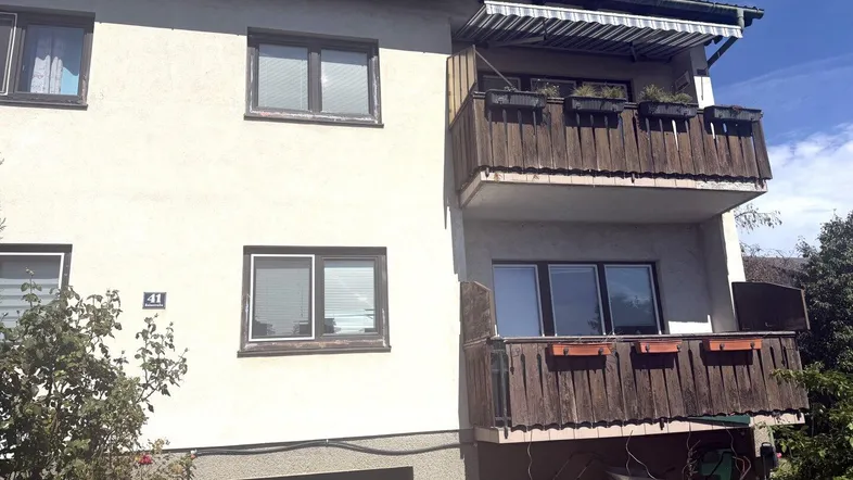Fassade eines Mehrfamilienhauses mit zwei Balkonen und einer Markise.
