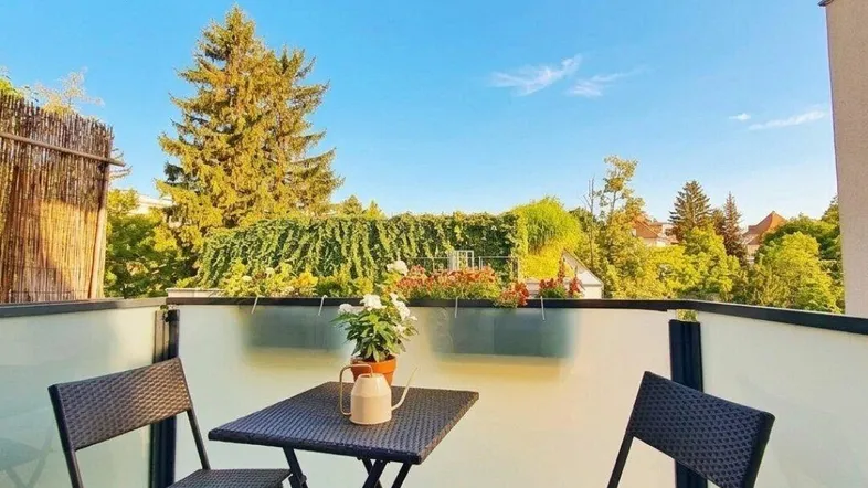 Heller Balkon mit Sitzgelegenheiten und Blick ins Grüne, ideal für entspannte Stunden im Freien.