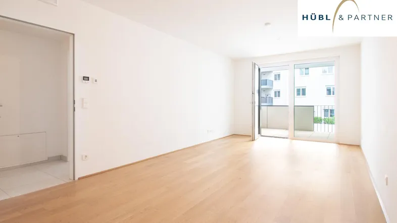 Helles, leeres Zimmer mit Holzboden und Zugang zu einem Balkon, ideal für individuelle Gestaltung.